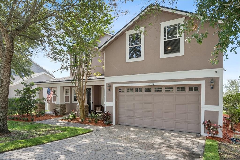 A two-story house with a tan stucco exterior, a stone-accented porch, and a paved driveway — 1727 SOUTHERN OAK LOOP, MINNEOLA, FL