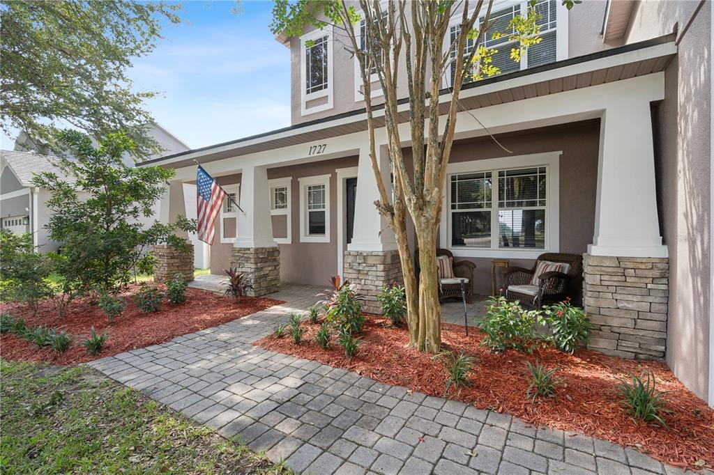 A two-story house exterior features a stone-accented front porch with a paved walkway and landscaping — 1727 SOUTHERN OAK LOOP, MINNEOLA, FL