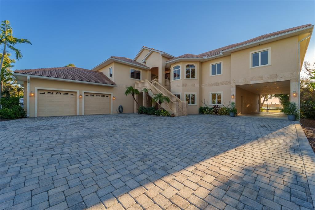 A large two-story house with a paved driveway, two-car garage, and an elevated front entrance — 1930 BAYSHORE DRIVE, ENGLEWOOD, FL