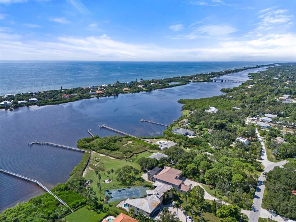 An aerial view shows a waterfront estate with a tennis court, docks, and lush landscaping — 1930 BAYSHORE DRIVE, ENGLEWOOD, FL