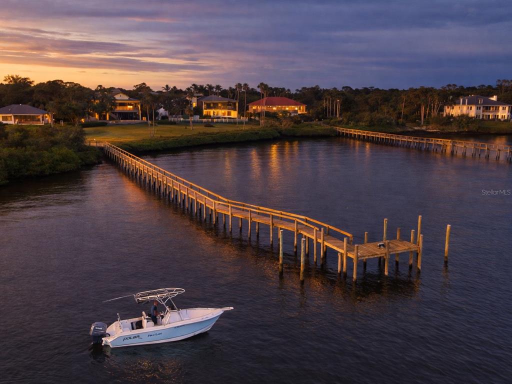 An aerial view shows a boat near a long wooden pier extending into the water — 1930 BAYSHORE DRIVE, ENGLEWOOD, FL