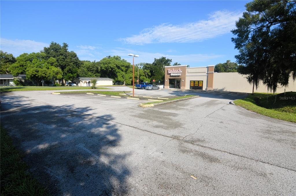 A large, paved parking lot sits in front of a commercial building under a blue sky — 5500 6TH STREET, ZEPHYRHILLS, FL