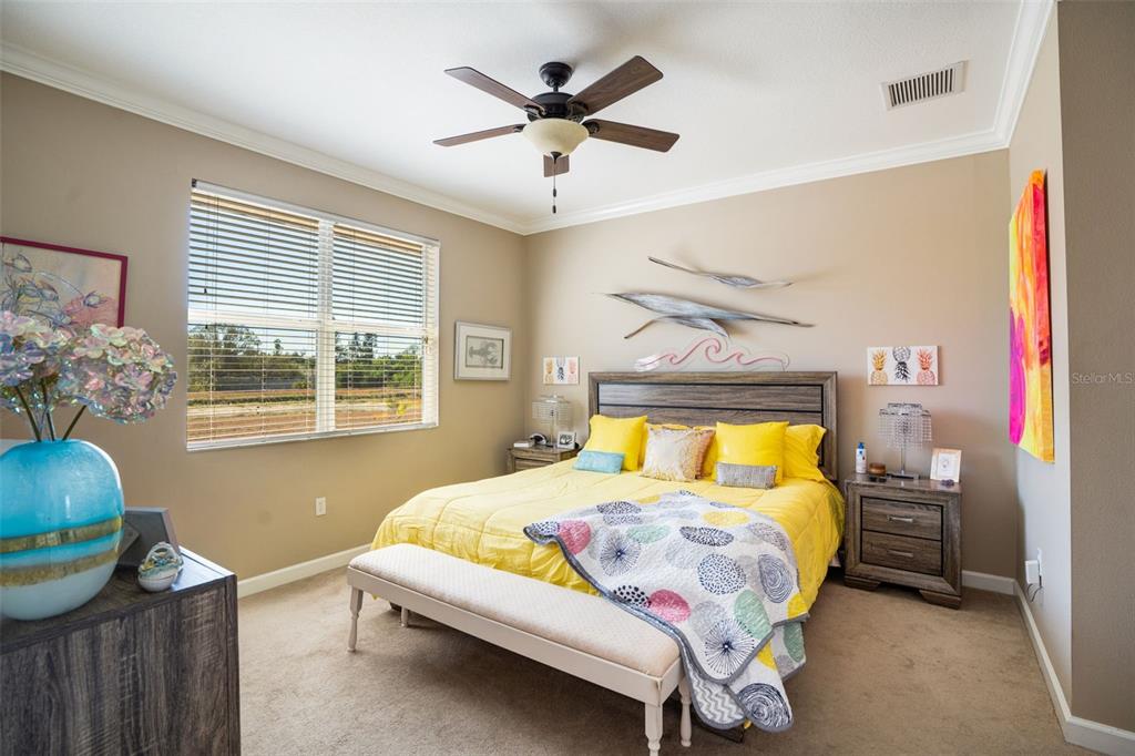 A bedroom features a yellow bed, a ceiling fan, and a window with blinds — 2890 ASHTON ROAD UNIT 5, SARASOTA, FL