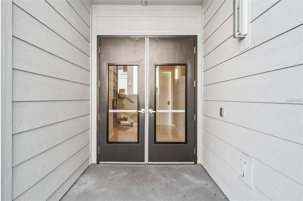 A set of double glass doors with metal frames sits at the entrance of a building — 7760 SANDY RIDGE DRIVE UNIT 112, REUNION, FL