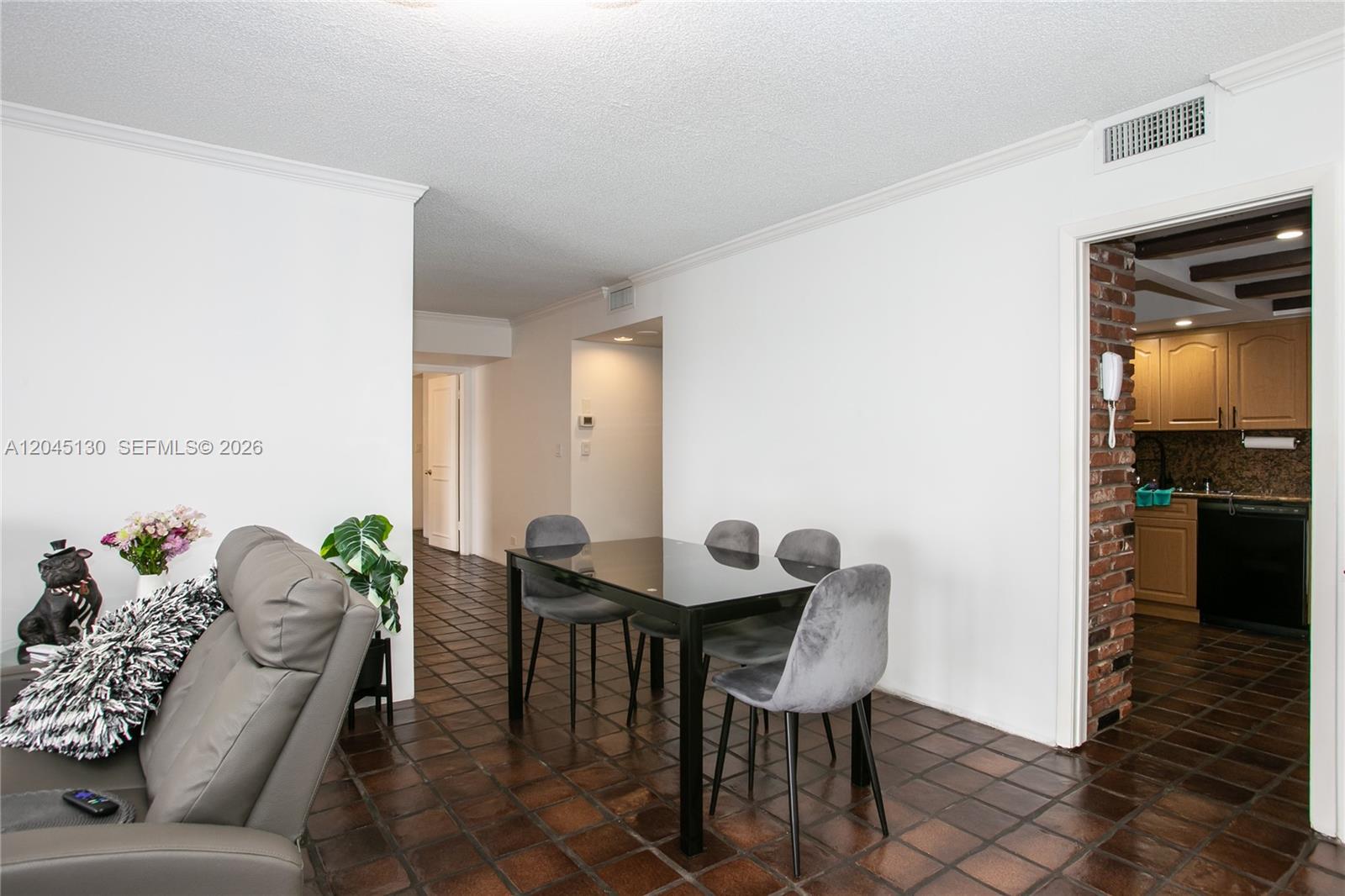 A dining area with a glass table and grey chairs sits on brown tiled floors — 1800 NE 114th St # 1207, Miami FL 33181, MIAMI, FL