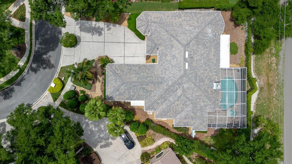 An aerial view shows a house with a gray shingled roof, a pool cage, and driveway — 13510 WESTSHIRE DRIVE, TAMPA, FL