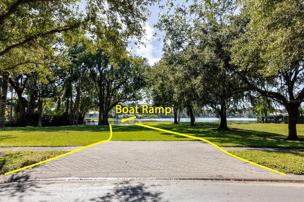 A paved driveway leads through a grassy yard toward a boat ramp at the lake — 13510 WESTSHIRE DRIVE, TAMPA, FL