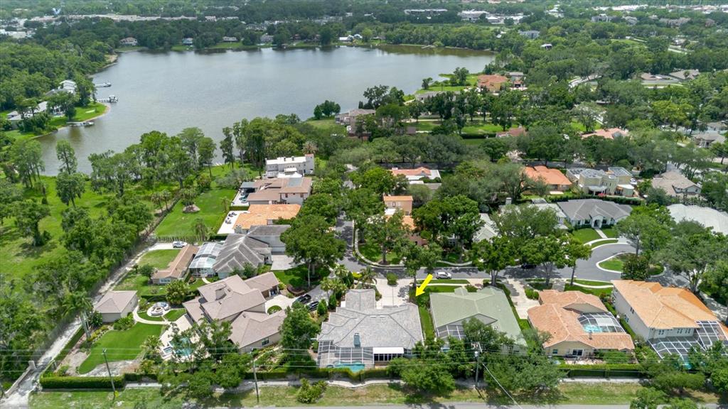 An aerial view shows a suburban neighborhood with houses, green lawns, and a large lake — 13510 WESTSHIRE DRIVE, TAMPA, FL