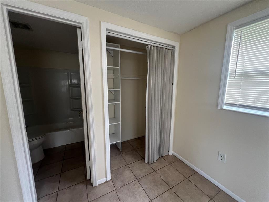 A room features tiled flooring, a bathroom doorway, a closet with shelving, and a window — 255 PINEAPPLE STREET UNIT 3, ENGLEWOOD, FL