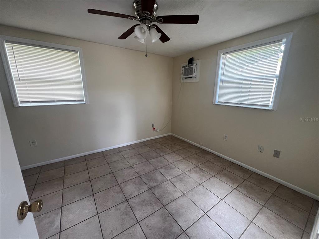 An empty bedroom features tile flooring, two windows with blinds, and a ceiling fan — 255 PINEAPPLE STREET UNIT 3, ENGLEWOOD, FL