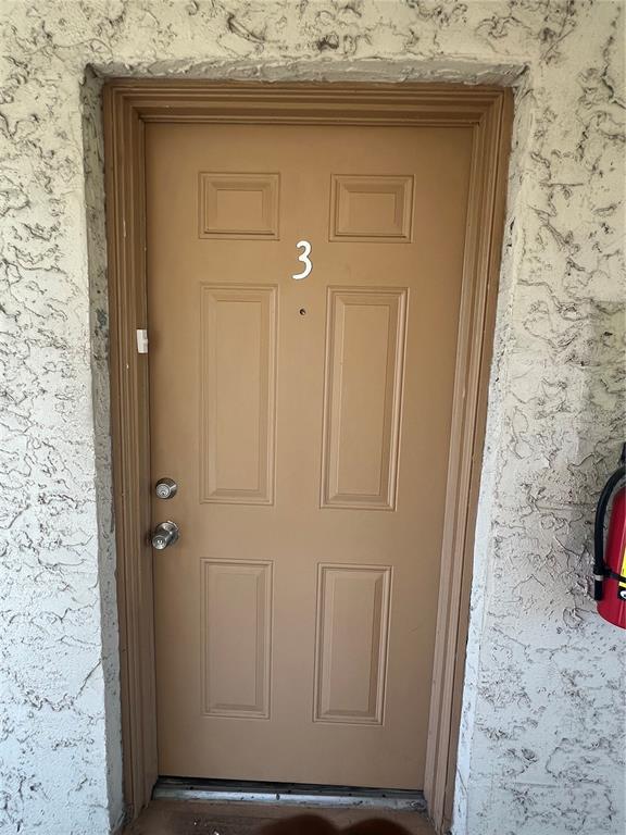 A tan-colored exterior door labeled with the number three is set in a textured wall — 1908 HONOUR RD UNIT 3, ORLANDO, FL