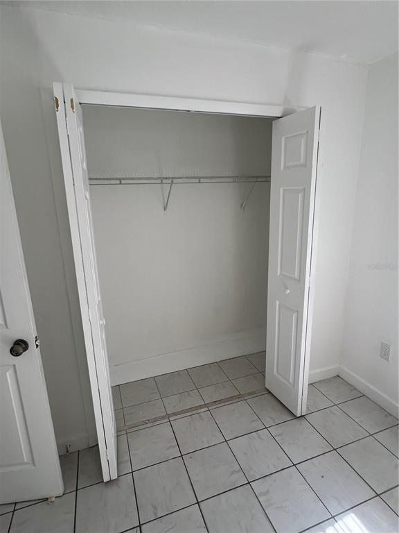 A closet with white bi-fold doors and a wire shelf sits in a tiled room — 1908 HONOUR RD UNIT 3, ORLANDO, FL