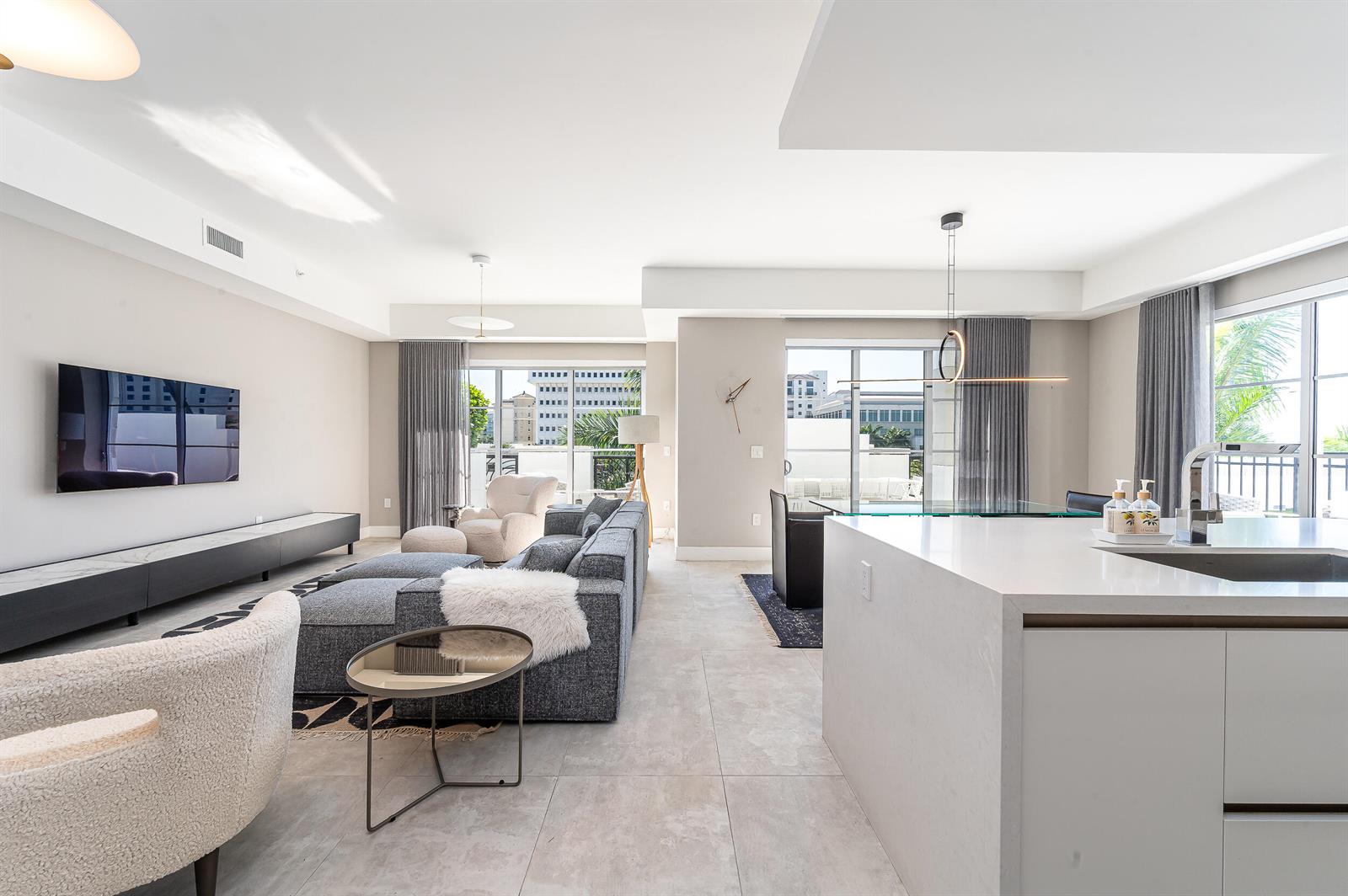 A modern open-concept living area features a kitchen island, gray sofa, and balcony views — 155 E Boca Raton Road # 416, Boca Raton FL 33432, BOCA RATON, FL
