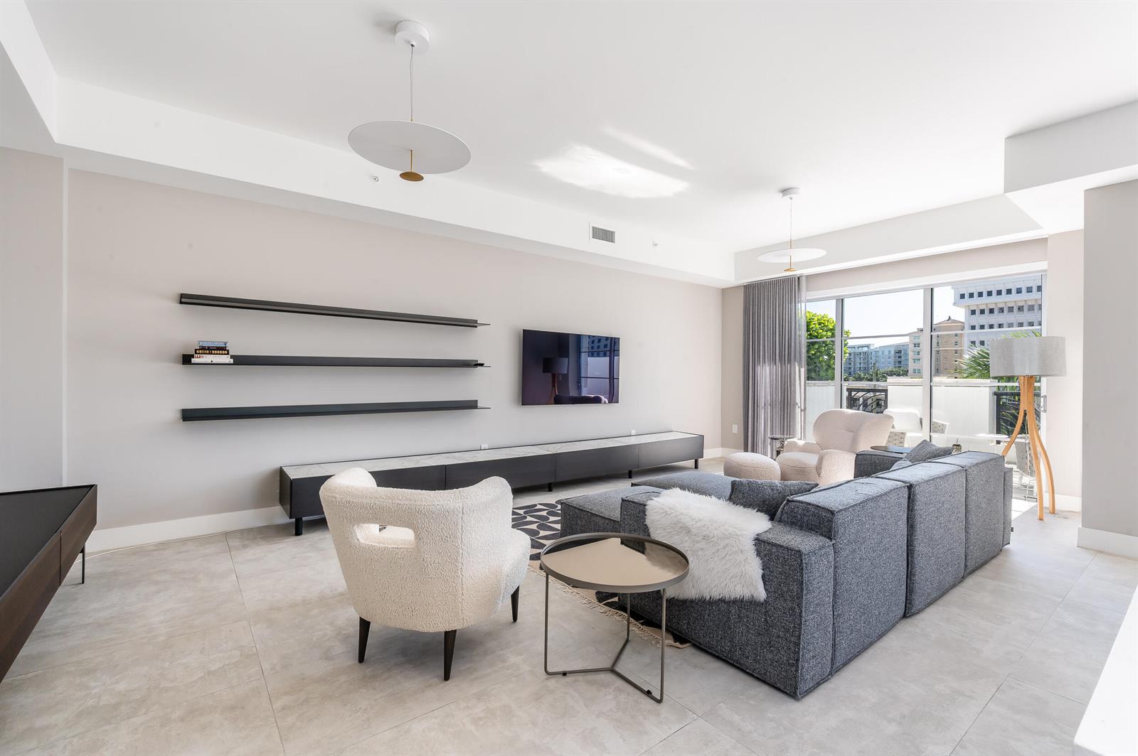 A modern living room features a gray sectional sofa, white accent chairs, and wall-mounted shelves — 155 E Boca Raton Road # 416, Boca Raton FL 33432, BOCA RATON, FL
