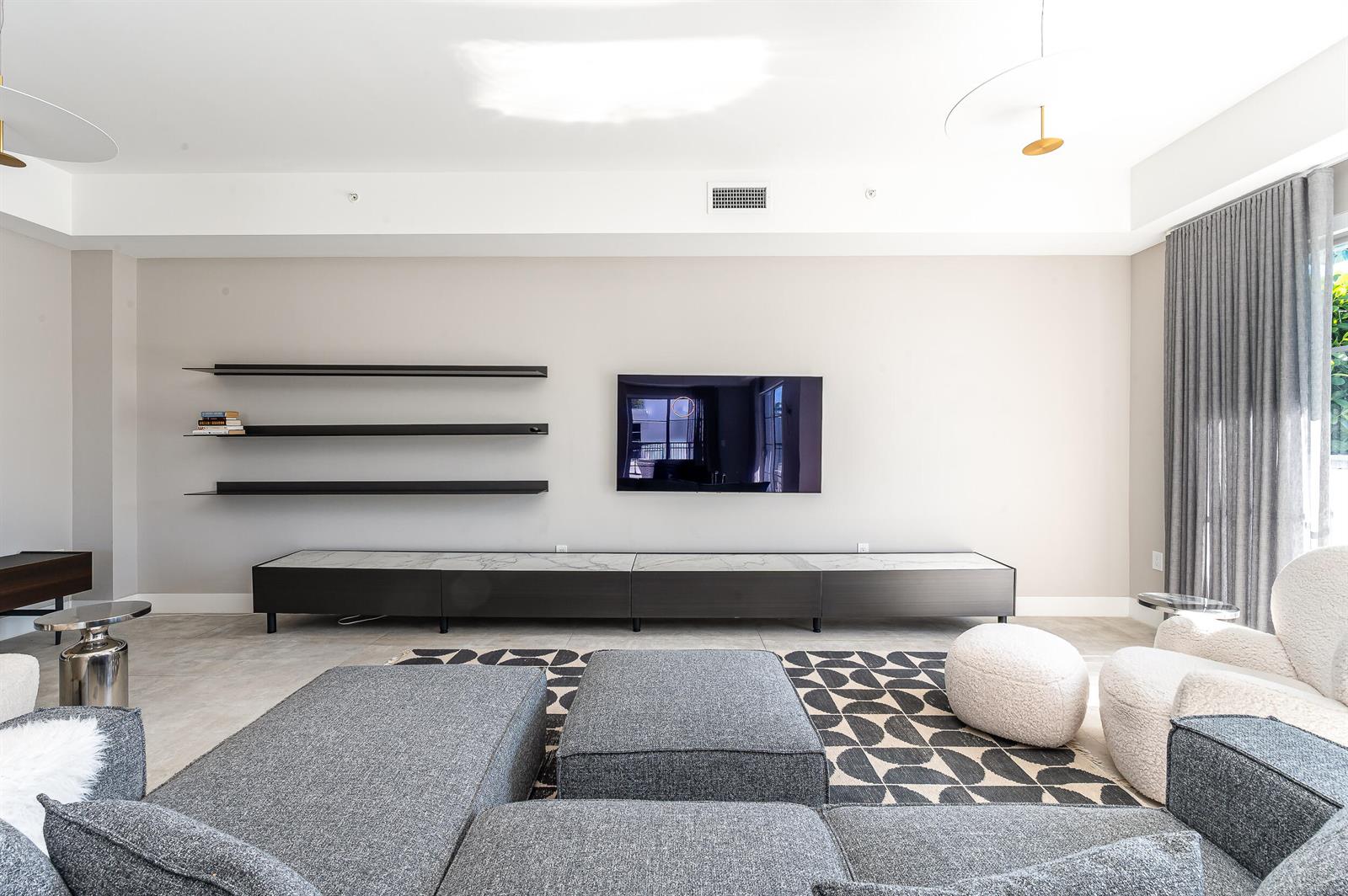 A modern living room features a wall-mounted television, floating shelves, and a long marble-topped console — 155 E Boca Raton Road # 416, Boca Raton FL 33432, BOCA RATON, FL