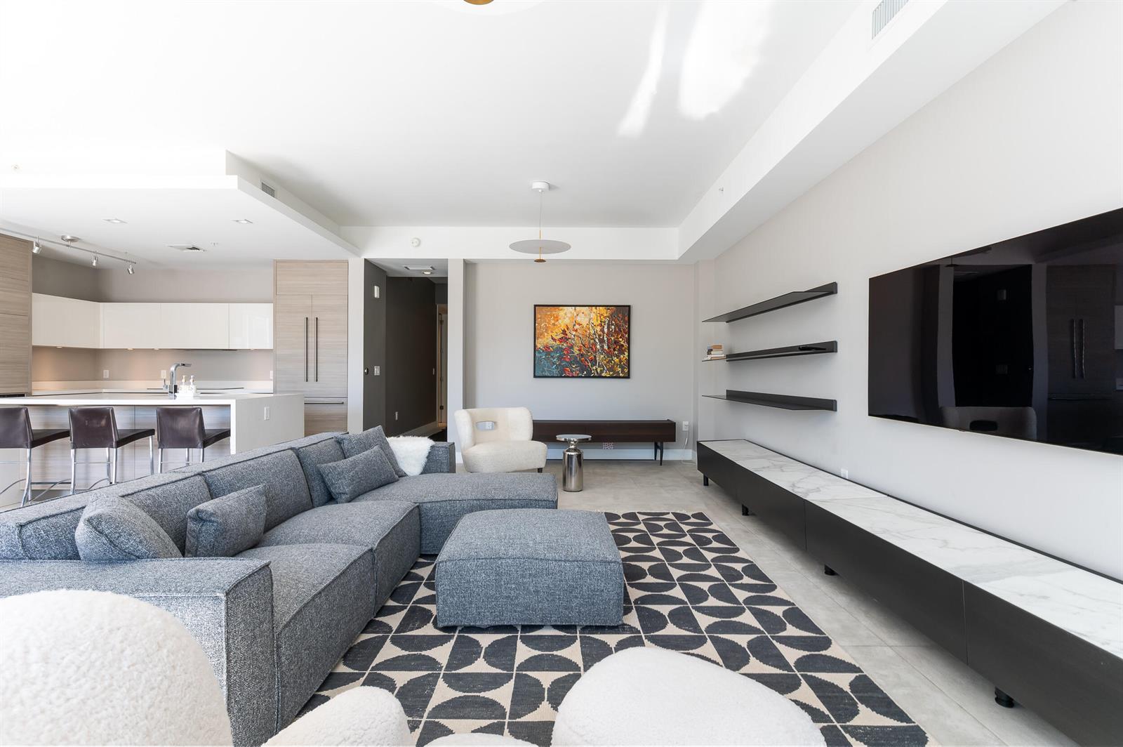A modern living room features a grey sectional sofa, patterned rug, and wall-mounted television — 155 E Boca Raton Road # 416, Boca Raton FL 33432, BOCA RATON, FL