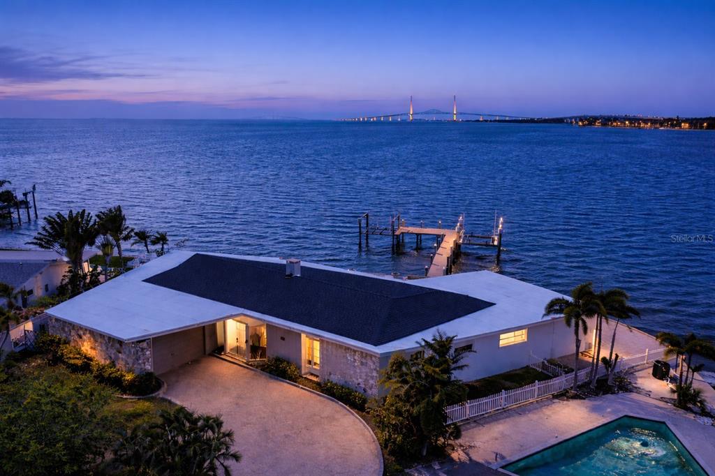 An aerial view of a waterfront house with a pool, dock, and bridge in distance — 2970 68TH AVENUE S, ST PETERSBURG, FL