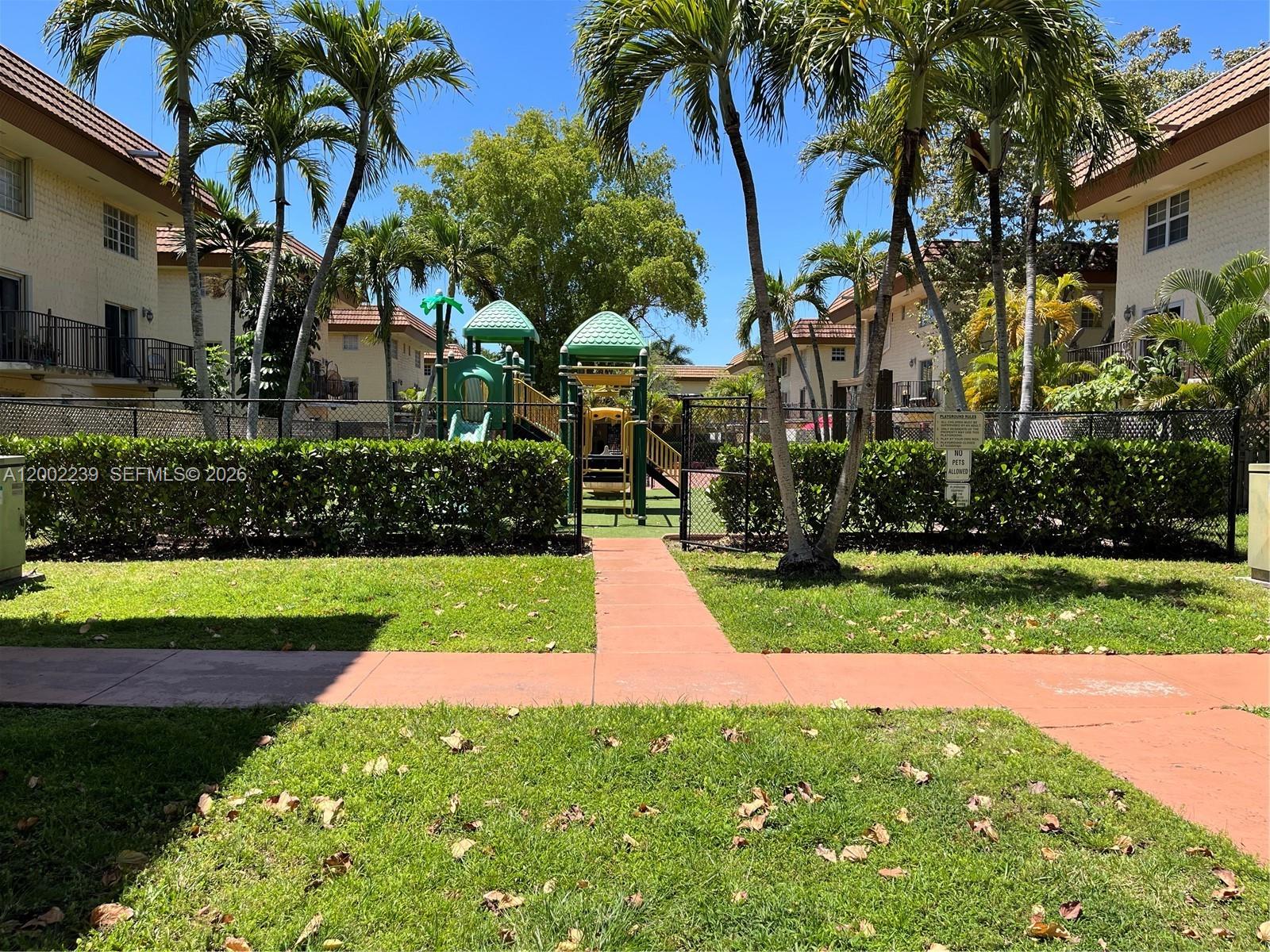 A fenced playground with slides and climbing equipment sits between two apartment buildings — 8650 SW 109th Ave # 111, Miami FL 33173, MIAMI, FL