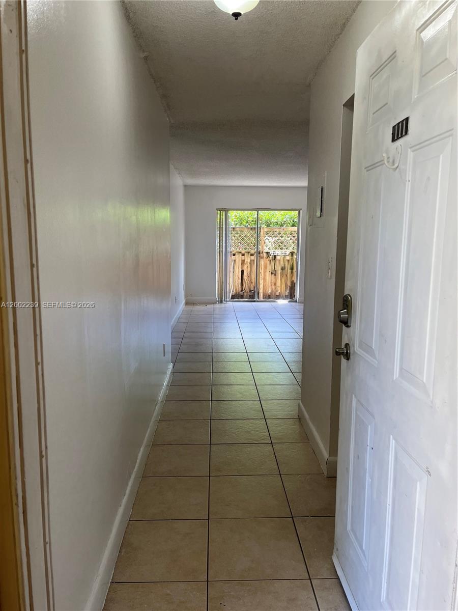 A tiled hallway leads from an open doorway toward a sliding glass door with patio views — 8650 SW 109th Ave # 111, Miami FL 33173, MIAMI, FL