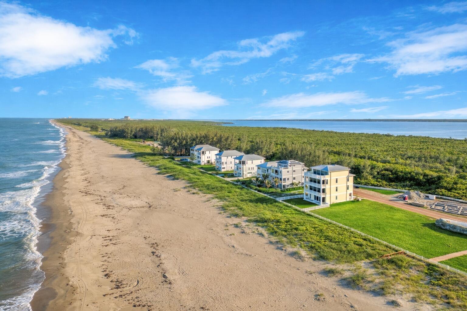 An aerial view of several multi-story houses situated along a sandy beach and dense forest — 5104 Watersong Way, Fort Pierce FL 34949, FORT PIERCE, FL