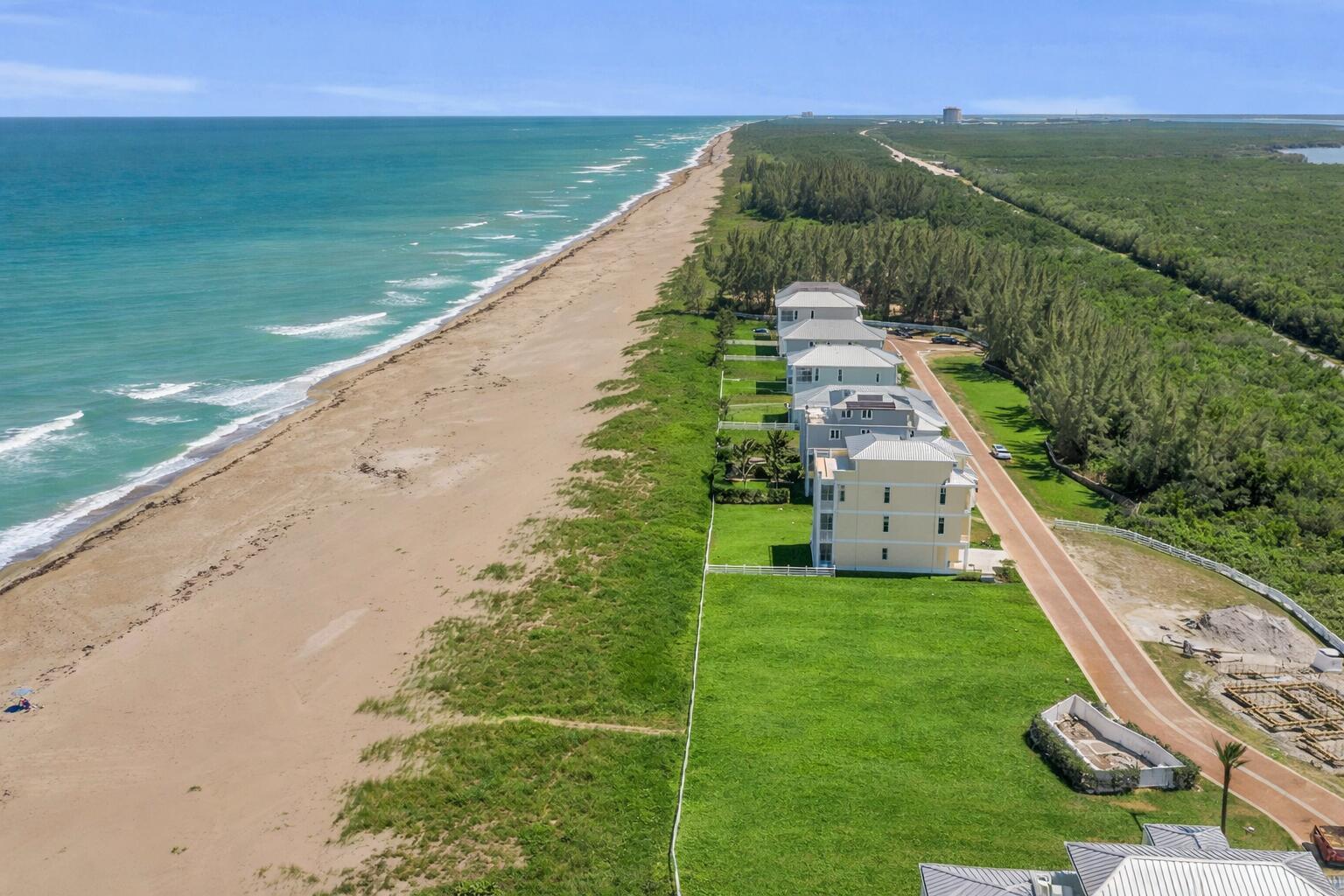 An aerial view shows several beachfront houses along a sandy coastline next to a forest — 5104 Watersong Way, Fort Pierce FL 34949, FORT PIERCE, FL