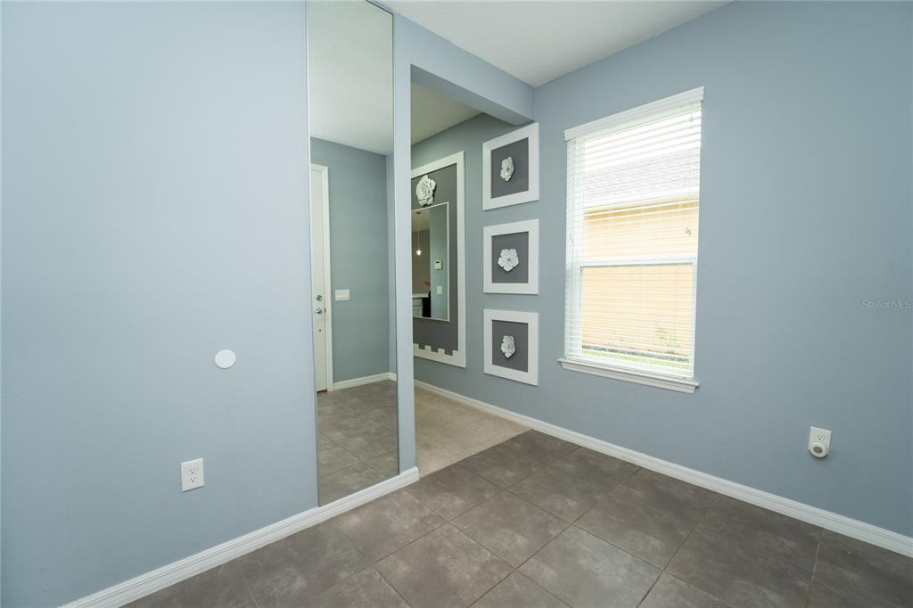 A room with light blue walls, tile flooring, a full-length mirror, and three framed decorations — 157 PALAZZO LANE, KISSIMMEE, FL