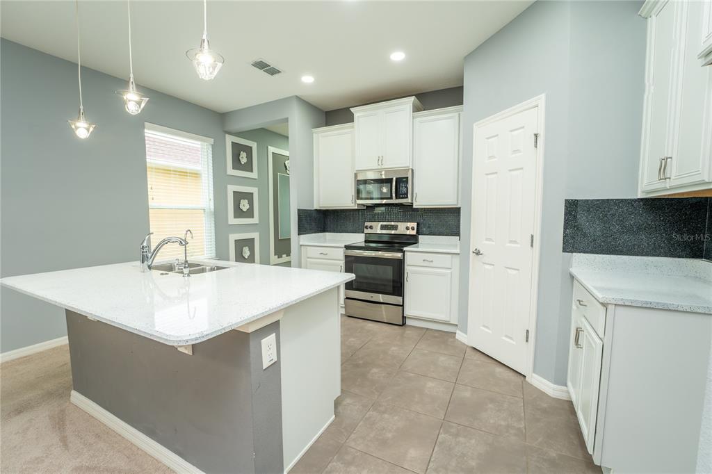 A kitchen with white cabinets, granite countertops, stainless steel appliances, and a central island — 157 PALAZZO LANE, KISSIMMEE, FL