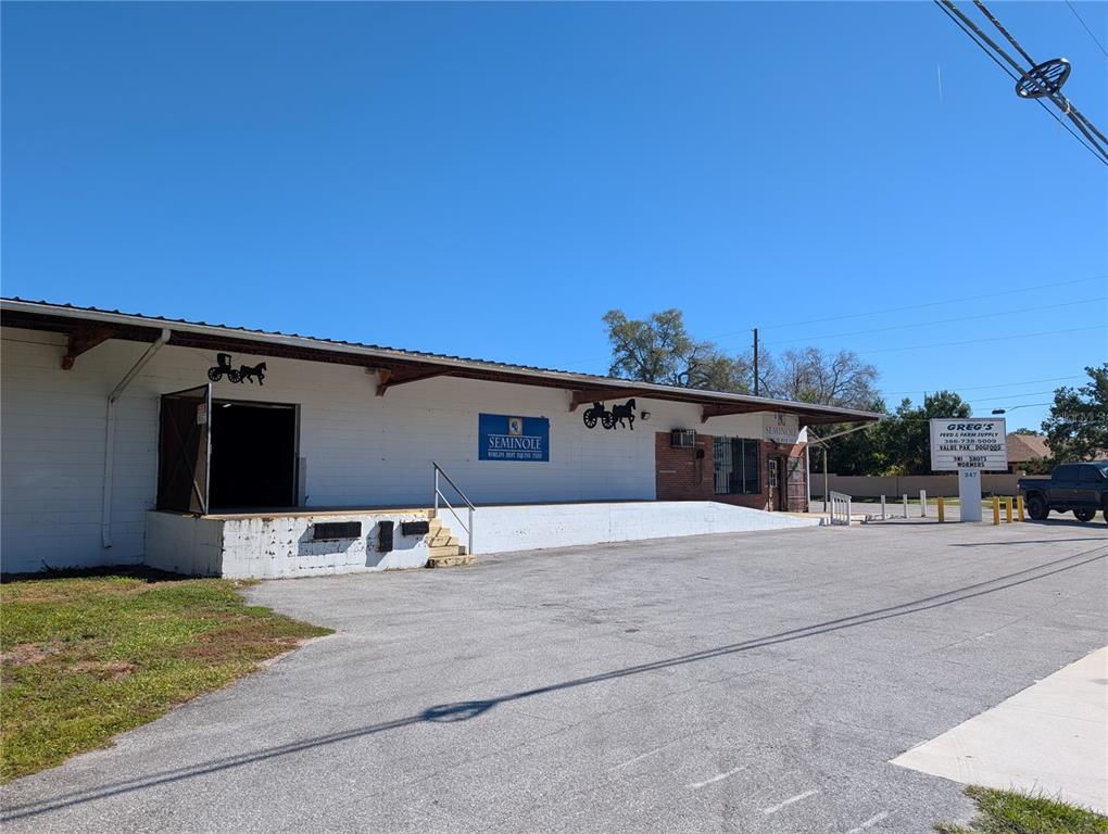 A white commercial building with a loading dock and a sign for Greg's Feed — 247 S AMELIA AVENUE, DELAND, FL