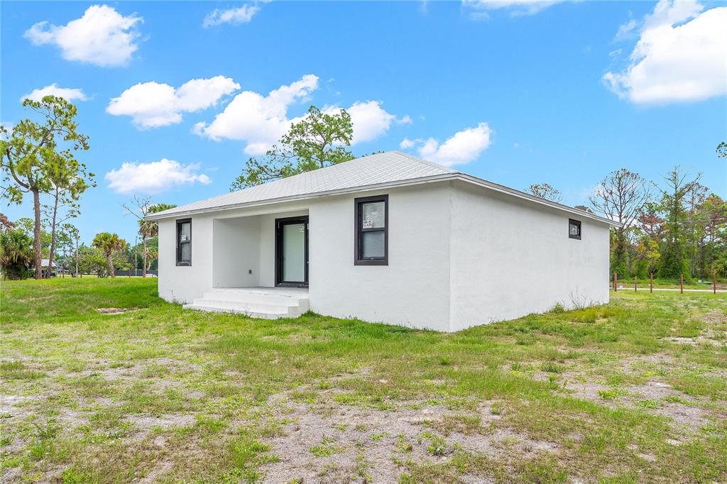 A white, single-story house with a hip roof and black-framed windows sits on grass — 660 S ZAMBRIA STREET, CLEWISTON, FL