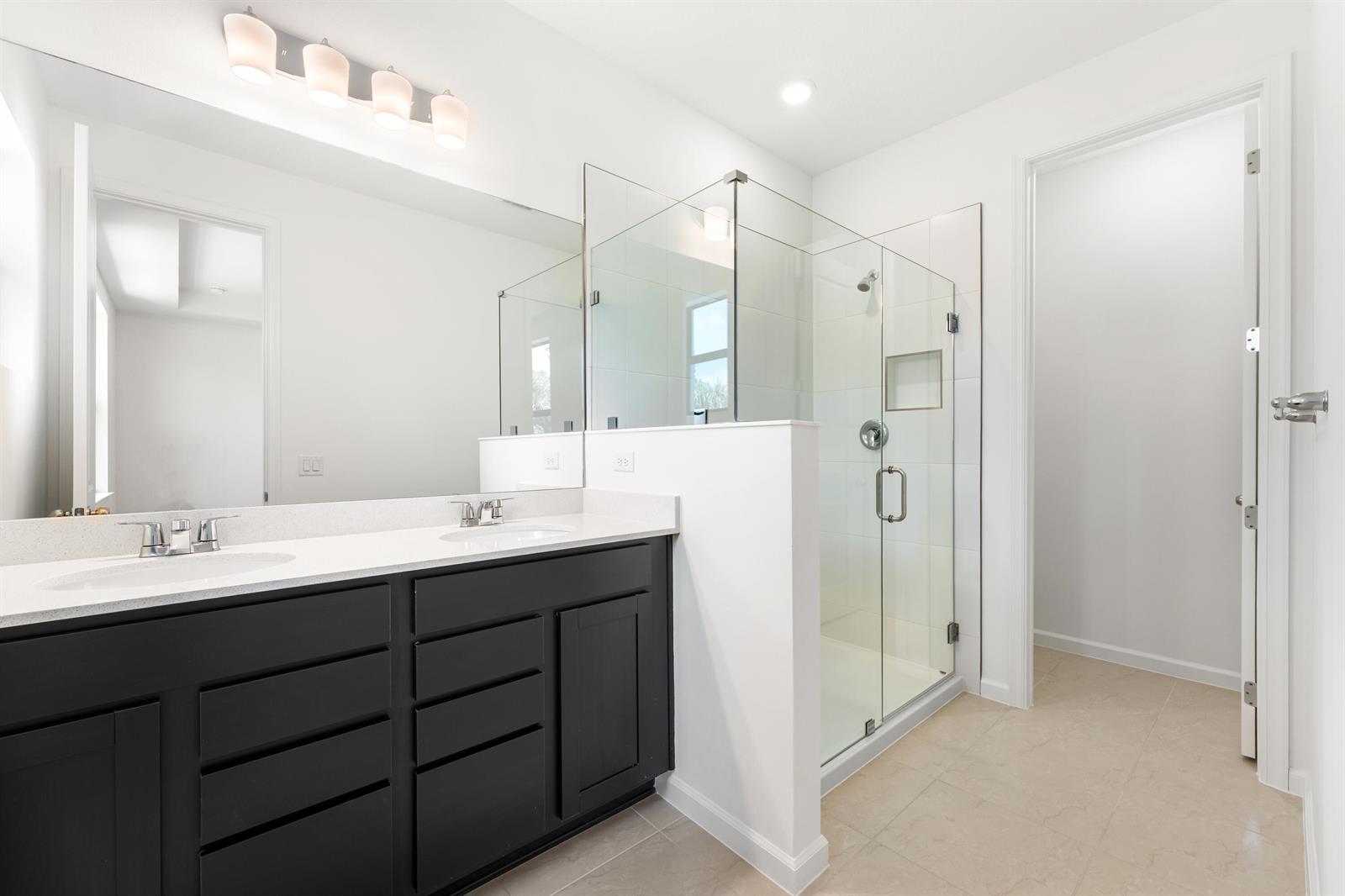 A bathroom features a dark vanity with a white countertop and a glass-enclosed shower — 4315 Efendi Drive, Lantana FL 33462, LANTANA, FL