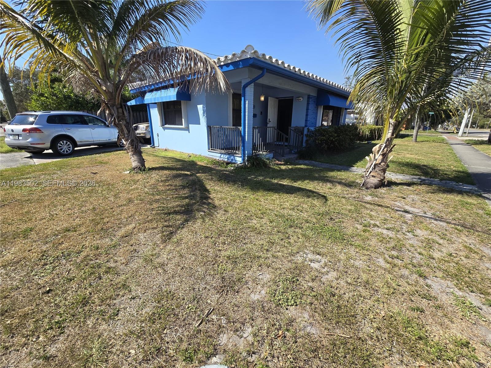 A blue single-story house with a tiled roof sits on a grassy lot with palms — 704 SW 2nd Ave, Dania Beach FL 33004, DANIA BEACH, FL