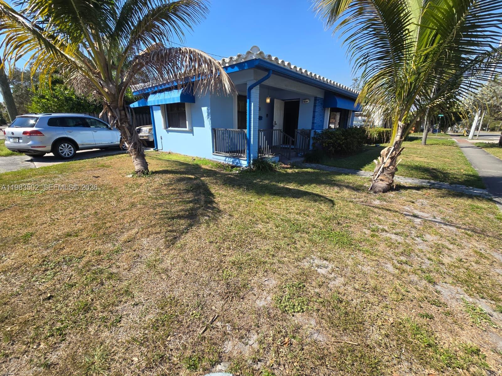 A light blue single-story house with a tiled roof sits on a grassy lot — 704 SW 2nd Ave, Dania Beach FL 33004, DANIA BEACH, FL