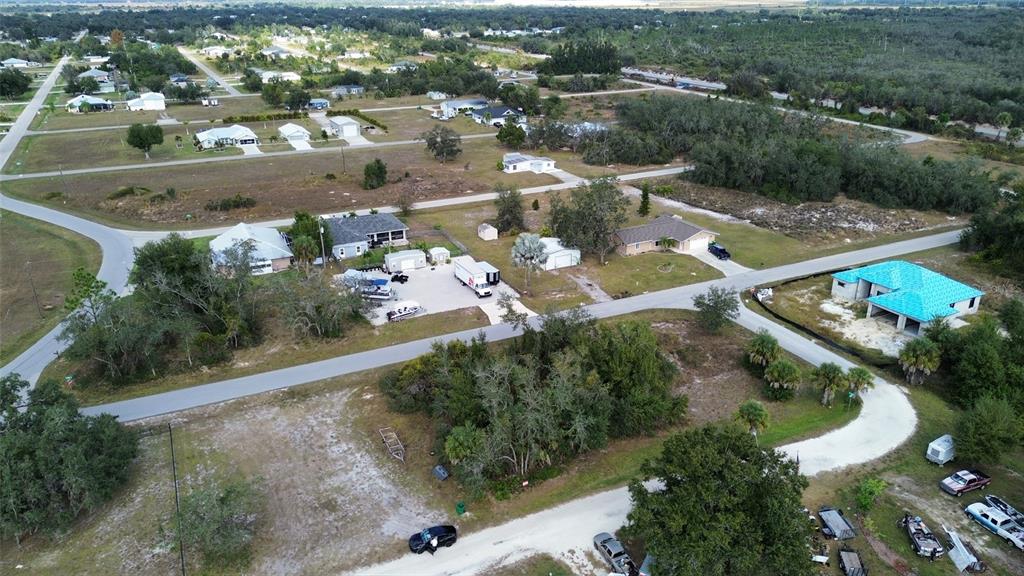 An aerial view shows a residential neighborhood with several houses, wooded areas, and paved roads — 29185 CYBELE STREET, PUNTA GORDA, FL