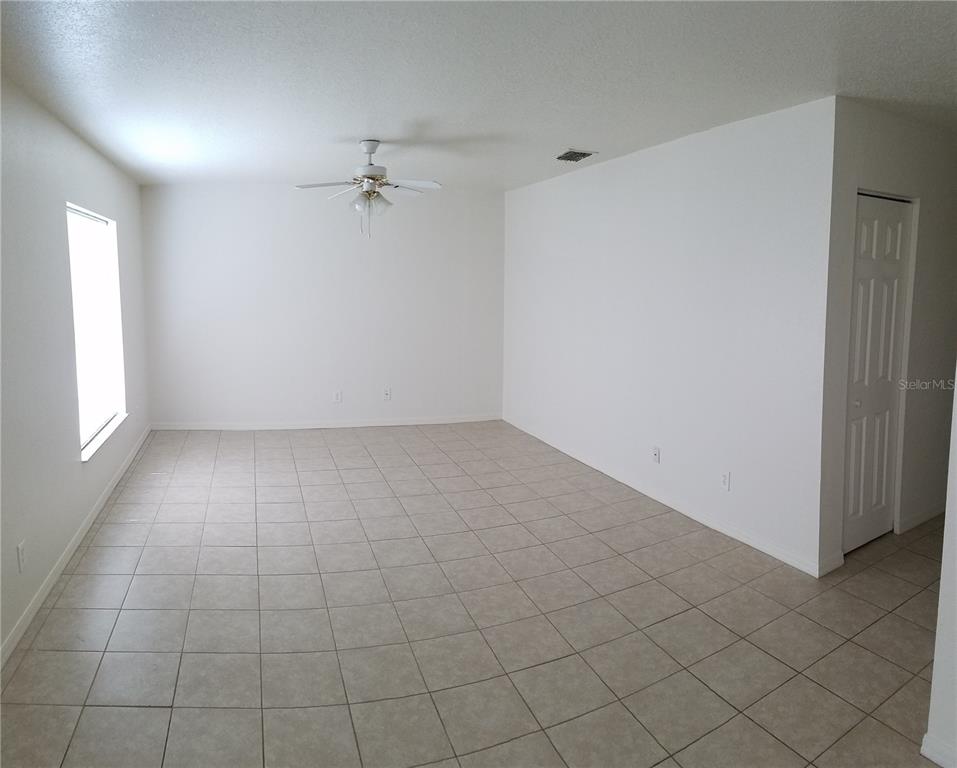 An empty room with white walls, light tile flooring, a ceiling fan, and a closet — 1673 SW 107TH LANE, OCALA, FL