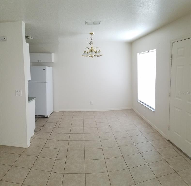 A dining area with tile flooring, a white refrigerator, and a hanging light fixture — 1673 SW 107TH LANE, OCALA, FL