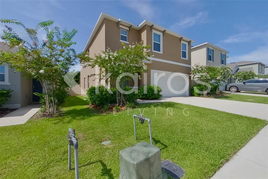 A two-story tan house with a garage and a front lawn under a blue sky — 31954 KATELIN CIRCLE, LEESBURG, FL