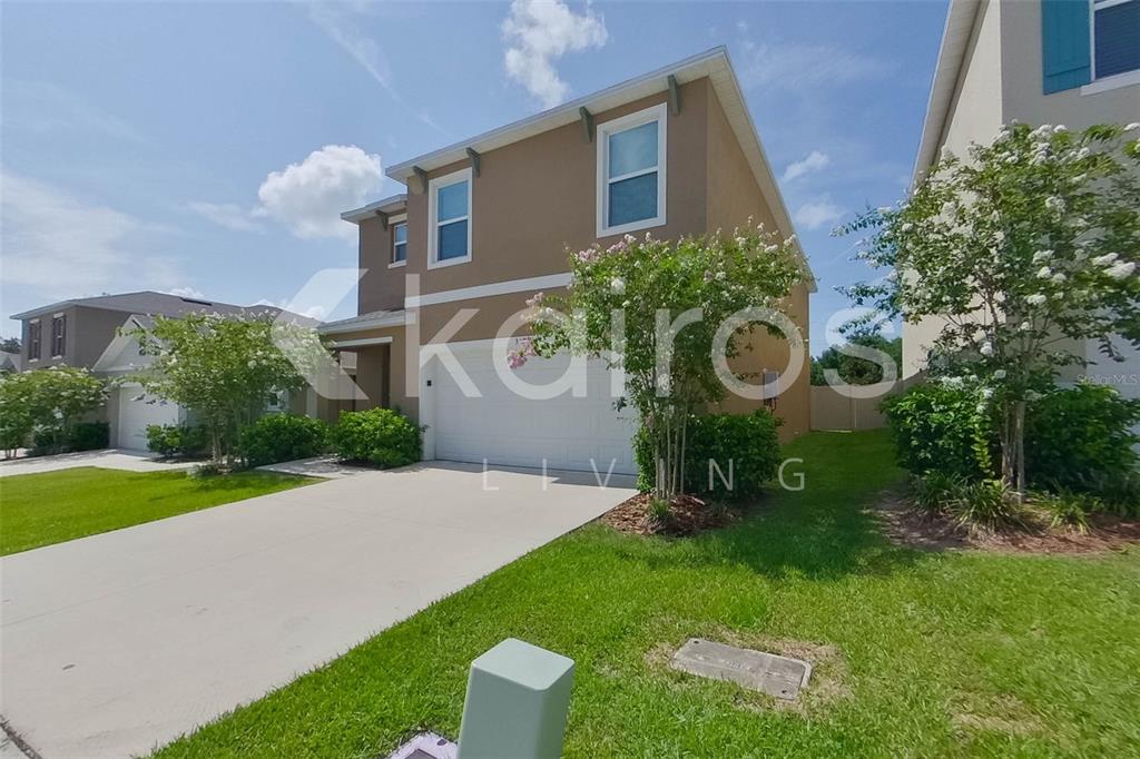 A two-story suburban house with a tan exterior, white garage door, and a concrete driveway — 31954 KATELIN CIRCLE, LEESBURG, FL