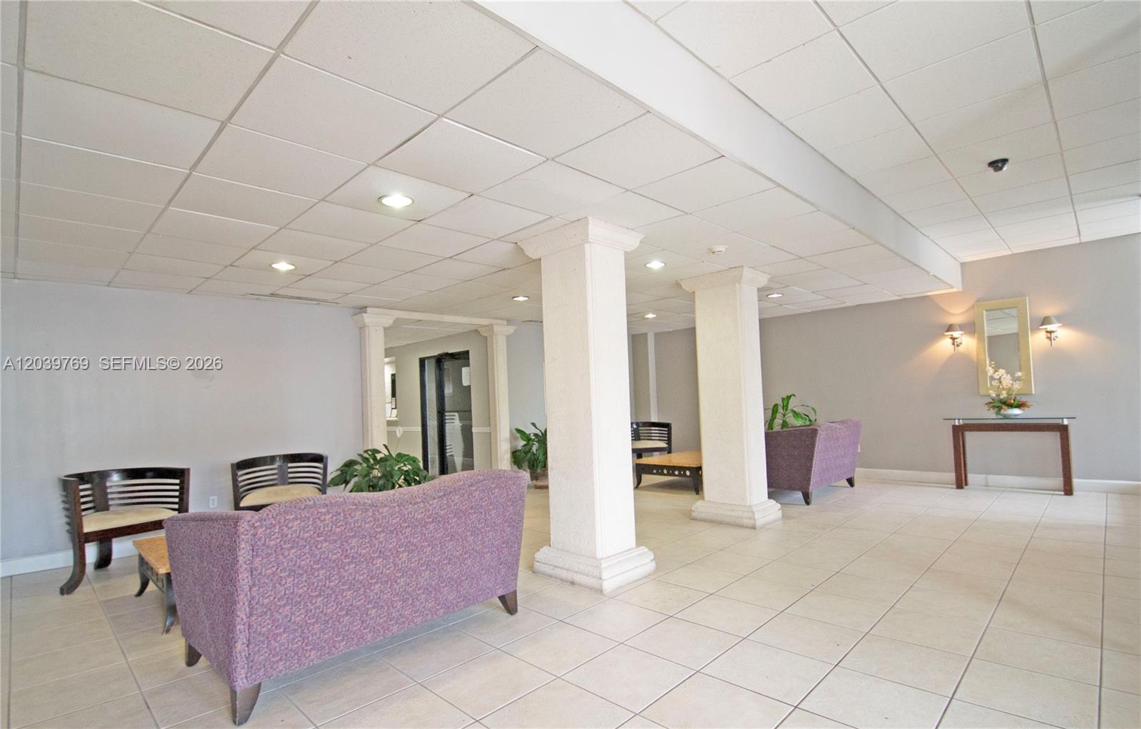 A lobby area features tiled floors, a drop ceiling, two support columns, and purple sofas — 2016 Bay Dr # 201, Miami Beach FL 33141, MIAMI BEACH, FL