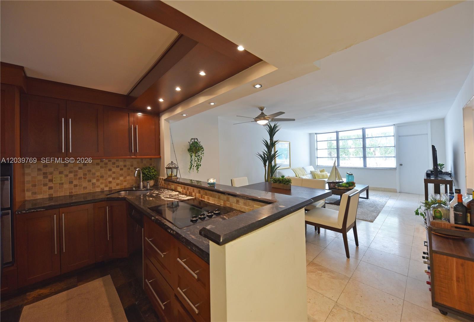 A kitchen with dark wood cabinets and granite countertops opens into a living area — 2016 Bay Dr # 201, Miami Beach FL 33141, MIAMI BEACH, FL