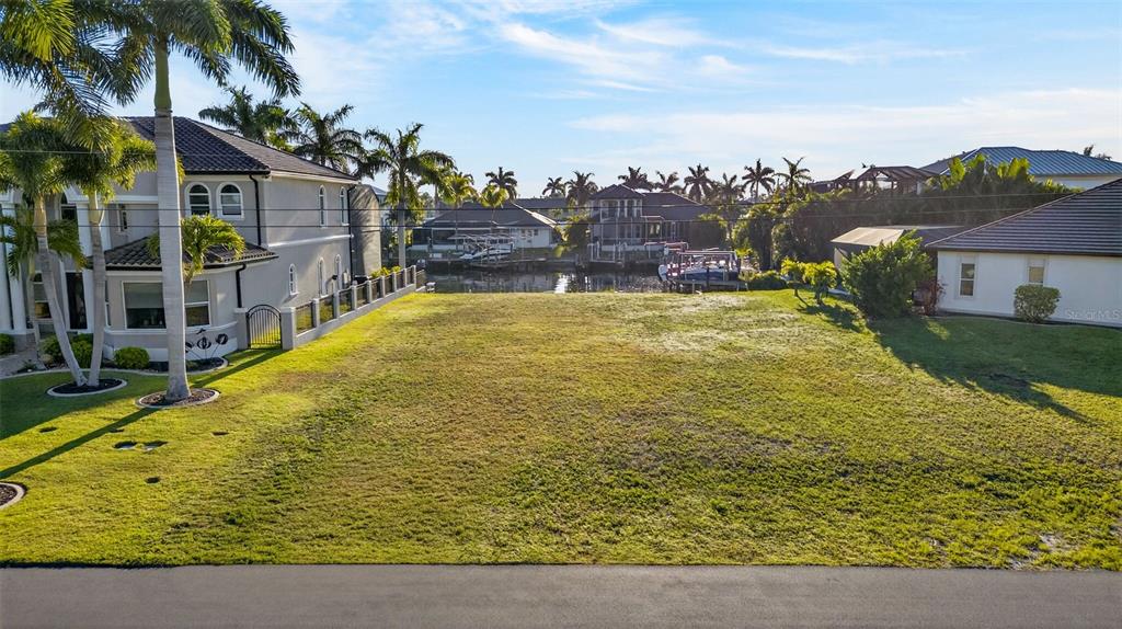 A vacant, grassy residential lot sits between two houses with a view of a canal — 5423 SW 17TH AVENUE, CAPE CORAL, FL