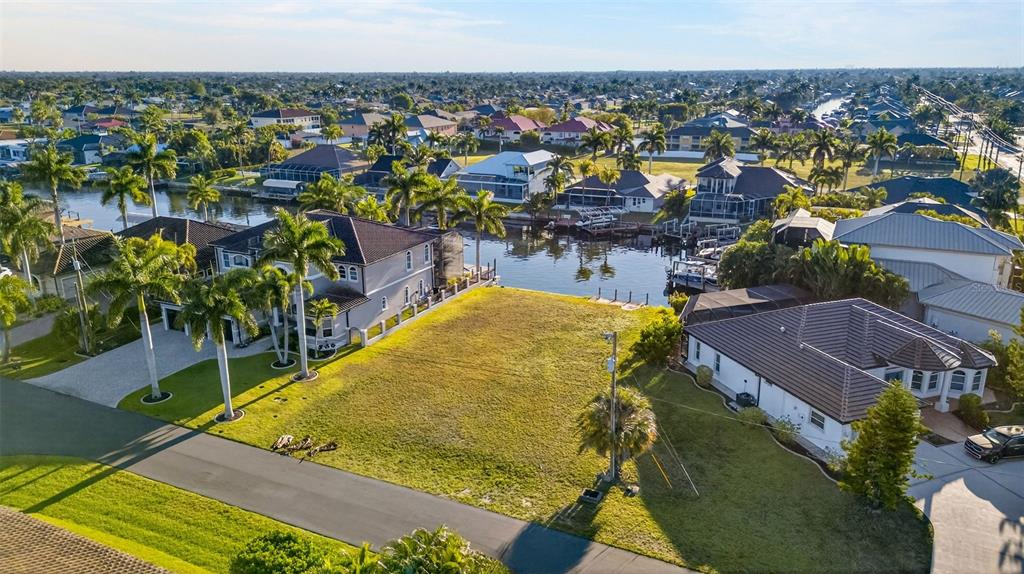 An aerial view shows a vacant waterfront lot situated between two residential houses — 5423 SW 17TH AVENUE, CAPE CORAL, FL