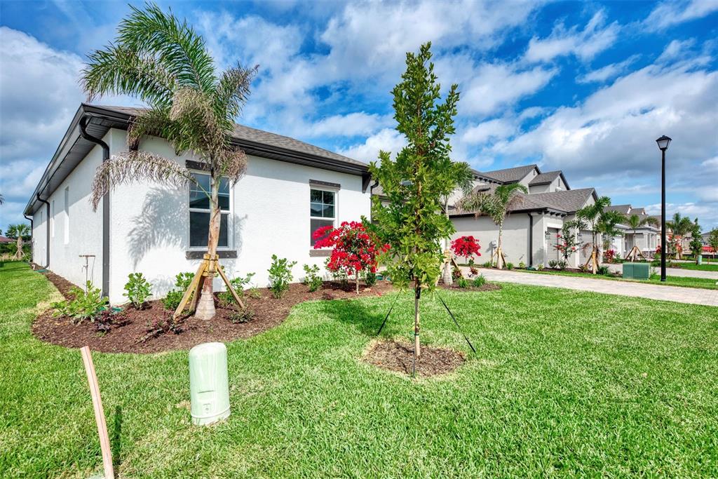 A white stucco house with a palm tree and landscaping in a suburban neighborhood — 5825 MILLENNIUM SILVER COURT, SARASOTA, FL