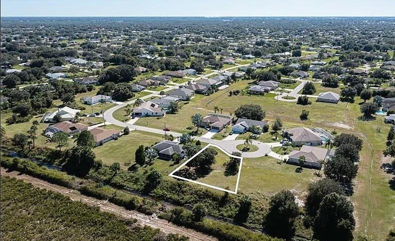 This aerial view shows a vacant residential lot outlined in white within a suburban neighborhood — 30 MOCHA COURT, PUNTA GORDA, FL