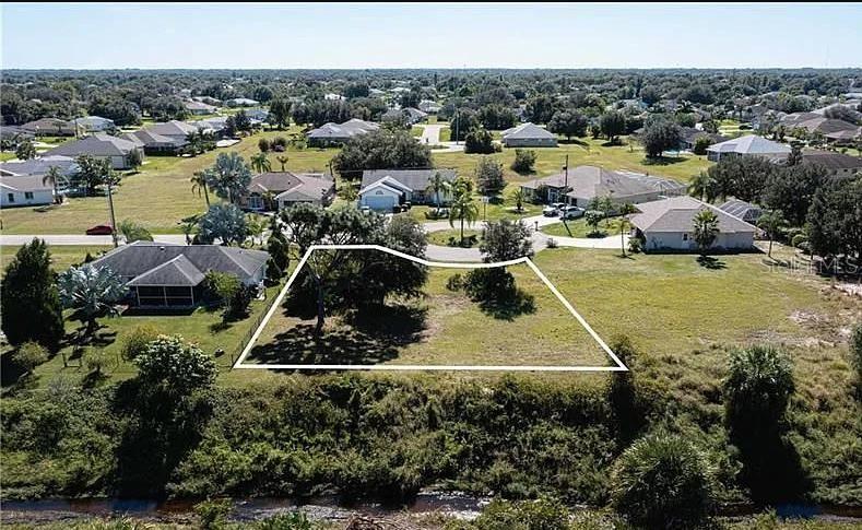 An aerial view shows a vacant residential lot outlined in white near a small canal — 30 MOCHA COURT, PUNTA GORDA, FL