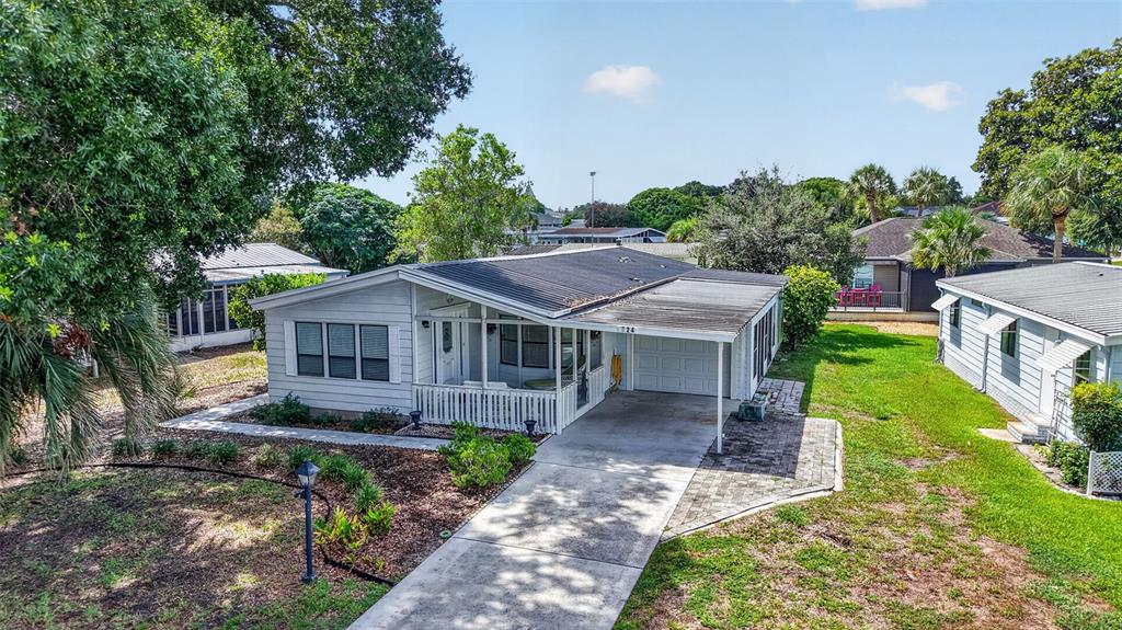 An exterior view of a single-story home with a metal roof and attached carport — 724 JASON DRIVE, THE VILLAGES, FL