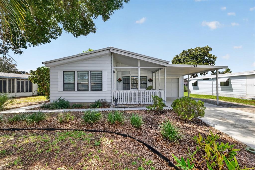 A single-story house with white siding, a front porch, and an attached carport — 724 JASON DRIVE, THE VILLAGES, FL