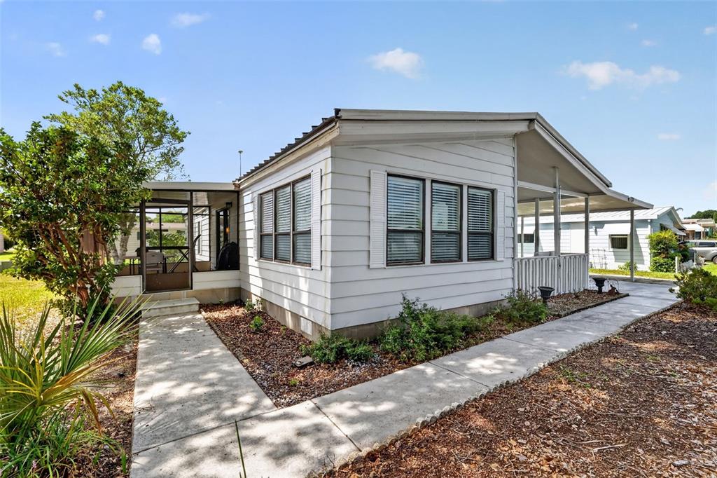 A white mobile home features a screened-in porch, horizontal siding, and a concrete walkway — 724 JASON DRIVE, THE VILLAGES, FL
