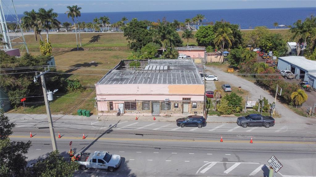 An aerial view shows a pink commercial building with a flat roof near the water — 185 E MAIN STREET, PAHOKEE, FL