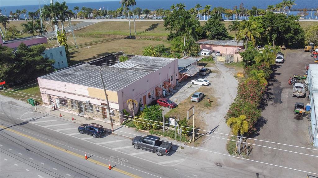 An aerial view shows a pink commercial building with a flat roof and parking lot — 185 E MAIN STREET, PAHOKEE, FL