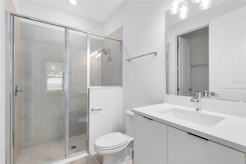 A modern bathroom features a glass-enclosed walk-in shower, a white vanity, and a toilet — 8472 SPERRY STREET, ORLANDO, FL